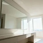 Modern bathroom with a large frameless mirror reflecting natural light, visually expanding the spacious and bright interior.
