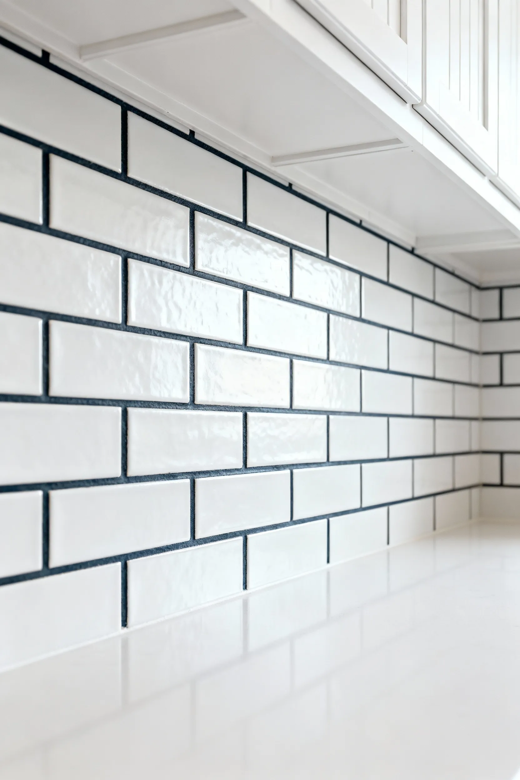 White subway tile kitchen backsplash with dark gray grout and white shaker cabinets.