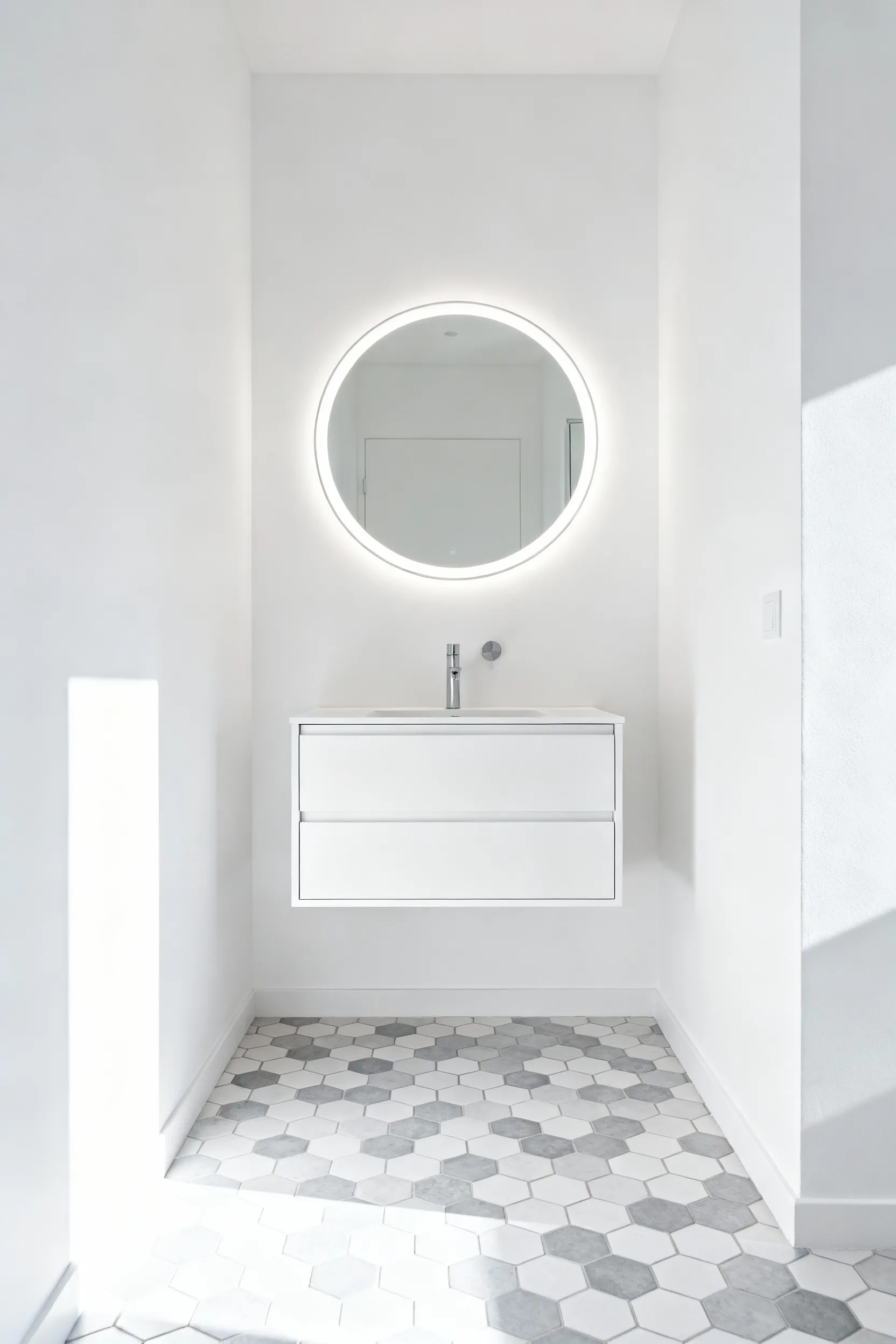 A modern small bathroom featuring a floating white wall-mounted vanity which exposes the continuous geometric floor tile underneath, demonstrating how reclaiming floor space makes the room feel significantly larger and airy.