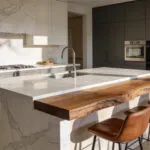A modern kitchen island with seating featuring a combination of cold marble surfaces and warm walnut wood to influence social flow.