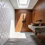 A compact bathroom featuring 3D hexagonal wall tiles and walnut wood accents to illustrate tactile decorating ideas for small spaces.