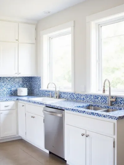 Kitchen with white cabinets and blue and white patterned tile countertop