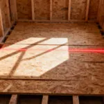 A photograph showing the structurally reinforced wooden subfloor and framework of a bathroom during the initial construction phase, highlighting the absolute levelness required for tiling longevity.